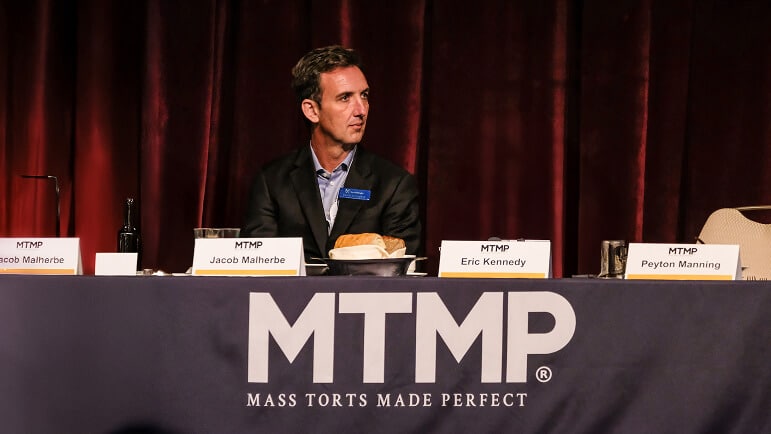 Jacob Malherbe seated on a panel at Mass Torts Made Perfect alongside named plaintiff-bar figures including Eric Kennedy and Peyton Manning
